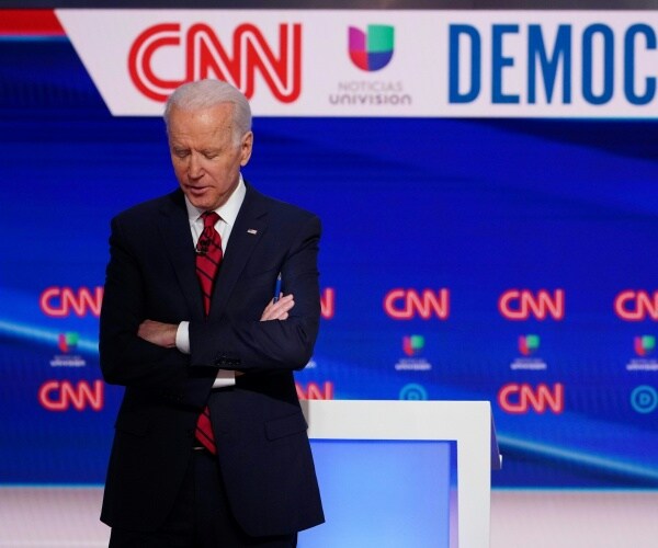 joe biden in a red tie on stage at the cnn democratic debate