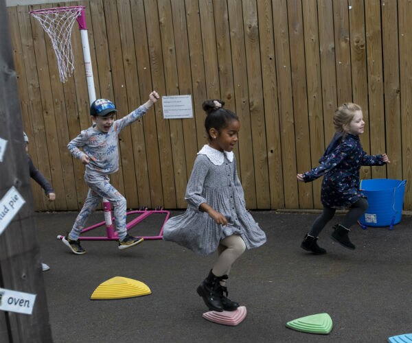 a cute little black girl, a white little boy and a white little girl all play together on a playground
