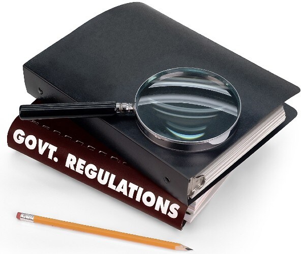a book labeled government regulations with a notebook on top and a magnifying glass on top of that