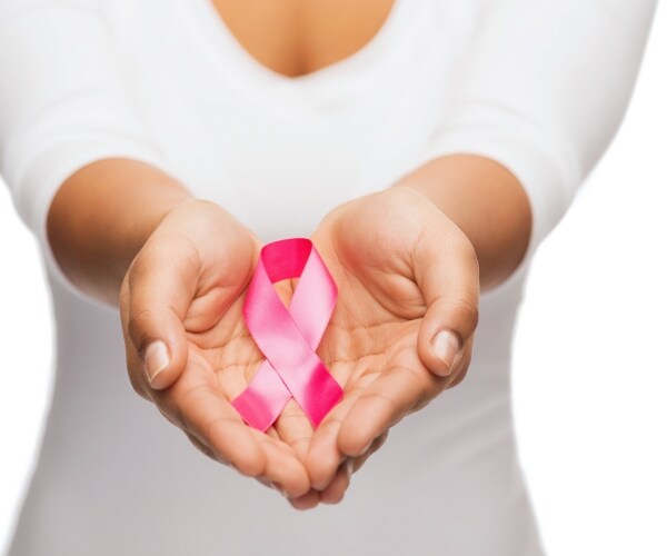 a woman holds a breast cancer awareness ribbon in her hands