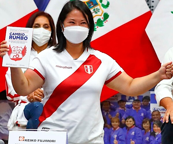 Keiko Fujimori holds up a book and gives a fist bump