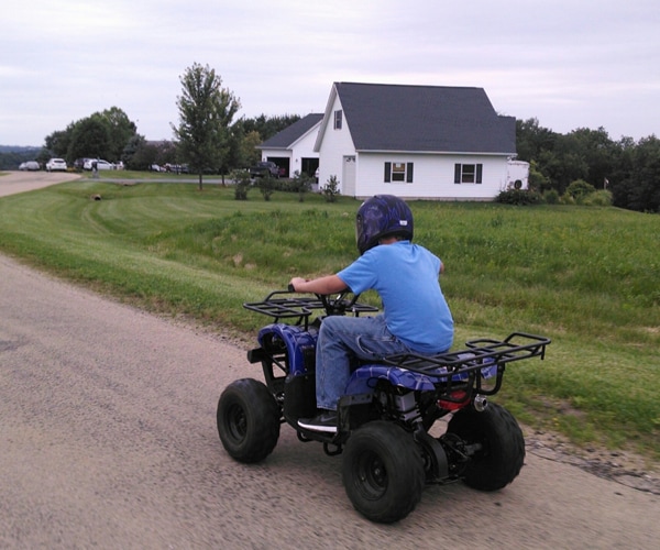 a kid riding an atv on a dirt road