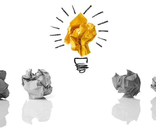 a row of wadded up pieces of paper with one raised up and decorated as a light bulb