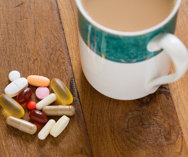 collection of pills next to coffee mug