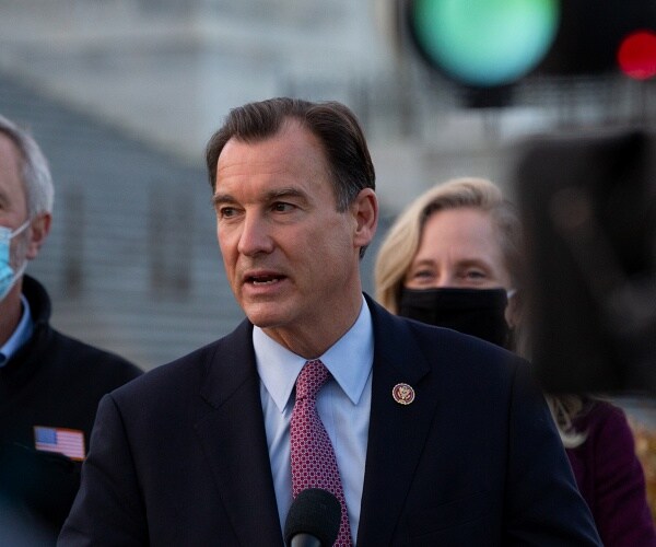 tom suozzi stands at podium