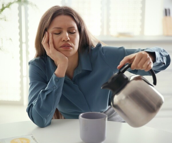 Sleepy woman pouring coffee into cup.