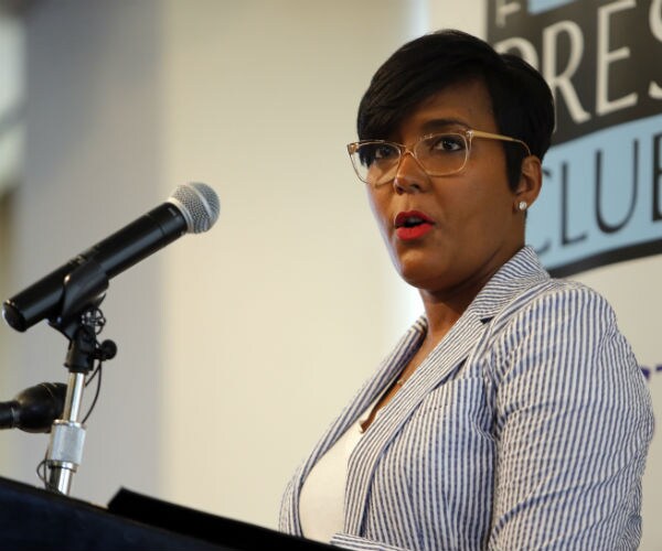 keisha lance bottom is seen wearing glasses in a blue and white seersucker jacket with a white camisole
