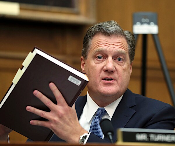 michael turner holds up a book as he speaks during a house committee hearing