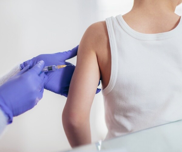 young child in white t-shirt getting vaccine
