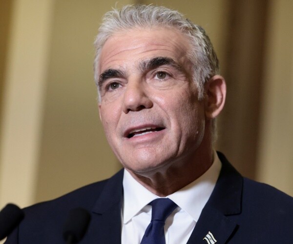 yair lapid speaks into a microphone