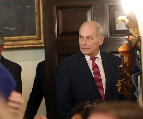 white house chief of staff john kelly walks through a door and looks back to his right over his shoulder