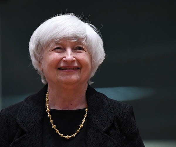 janet yellen smiles as she enters room