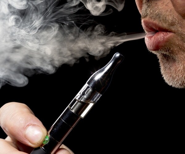 close-up of man exhaling smoke from e-cigarette