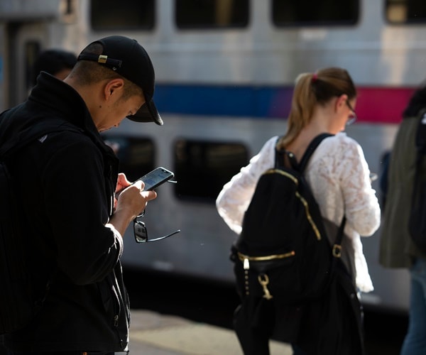 people read their cell phones waiting for a train