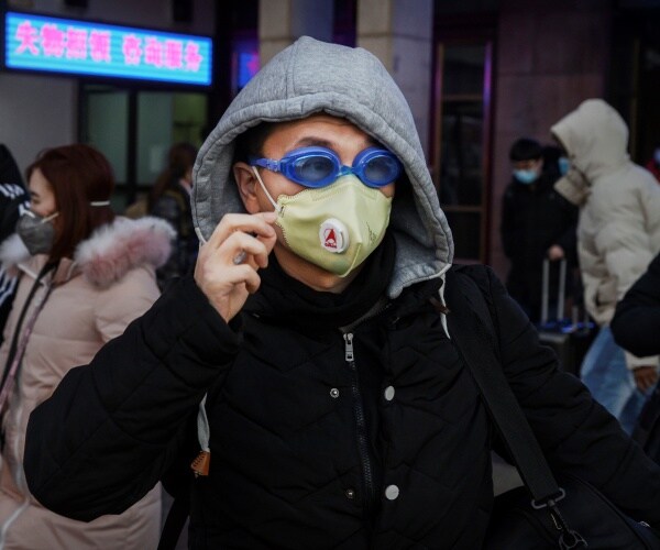 man wears a gray hoodie and black jacket with a yellow mask and goggles