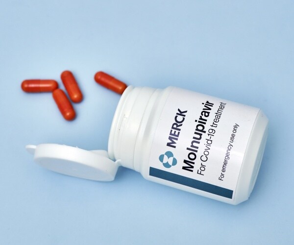 bottle of molnupiravir (Lagevrio) by Merck spilling some pills out on table