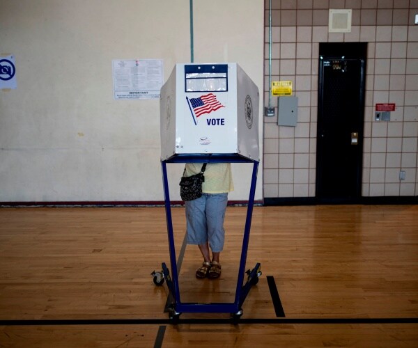 woman wearing jeans votes at a booth at a polling place