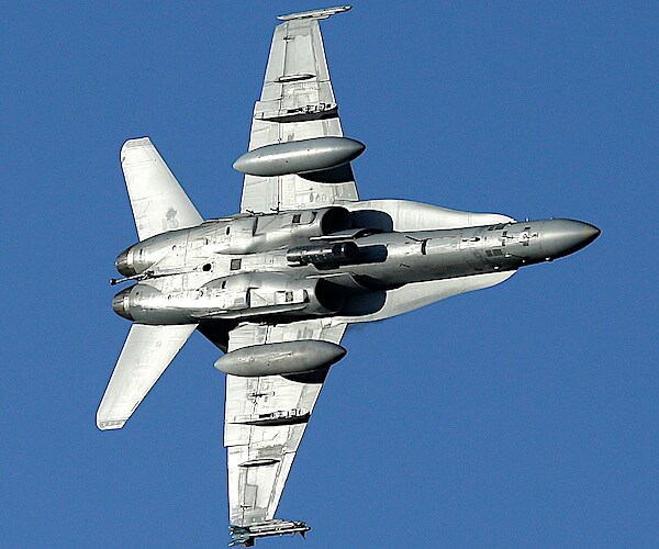 a hornet jet banks, showing its underbelly, over the nicknamed star wars canyon in death valley national park