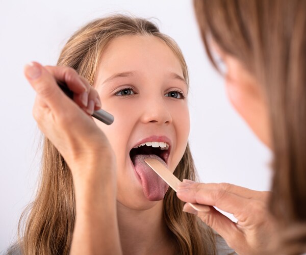 a doctor examining a girl's throat