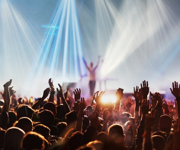 people in a crowd at a concert with performer on stage