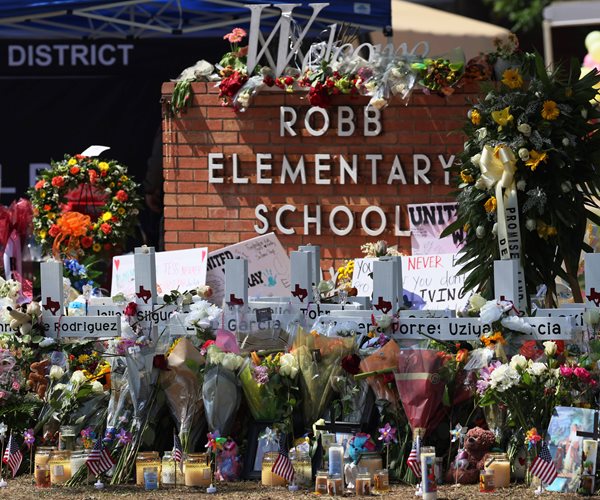 Sign covered in flowers and other tokens of remembrance.