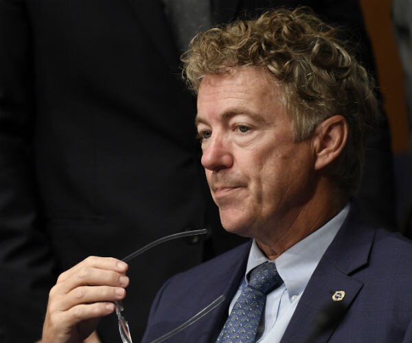 rand paul holds his glasses as he grimaces during a break in his media scrum