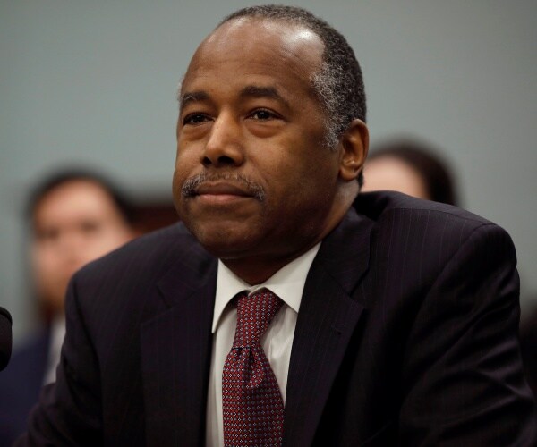 ben carson sitting down in a black suit and burgundy patterned tie