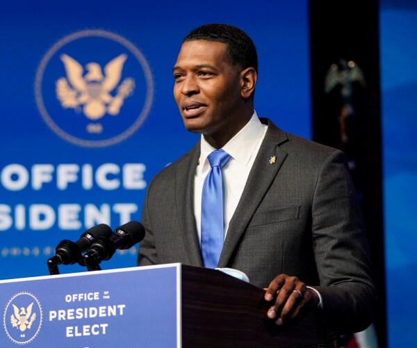 michael regan speaks into a microphone