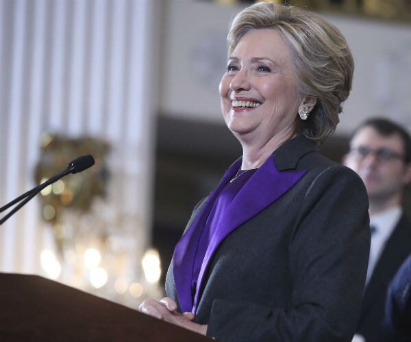 hillary clinton is shown smiling, standing at a podium