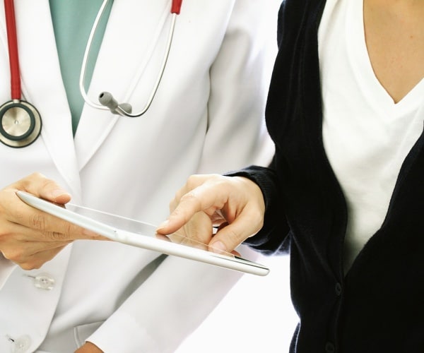 patient pointing to a tablet screen, asking doctor questions