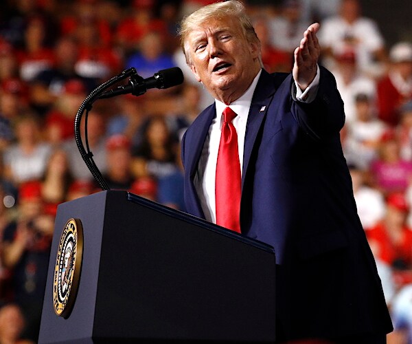 president donald trump points to his left in front of a large campaign rally crowd