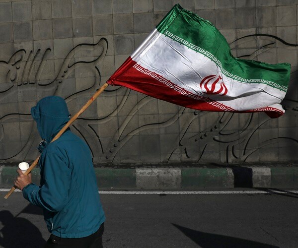 a man carries an iranian flag