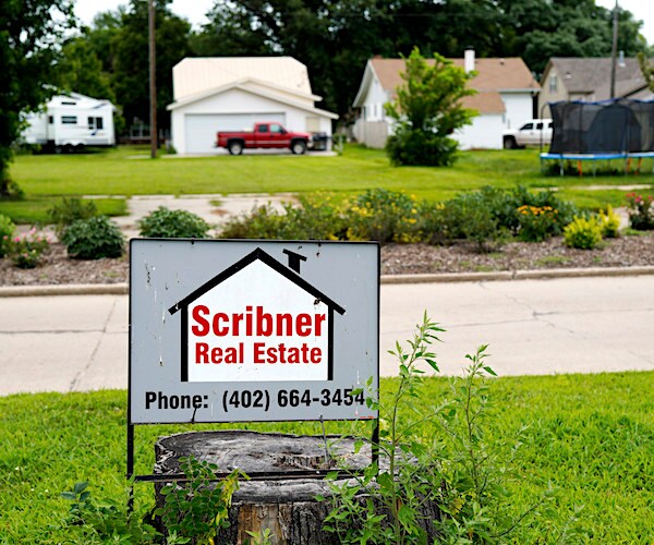 a real estate sign is planted in front of homes in nebraska
