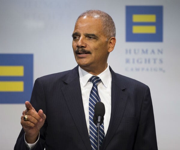 eric holder is shown in a dark suit, white dress shirt and blue and white striped tie