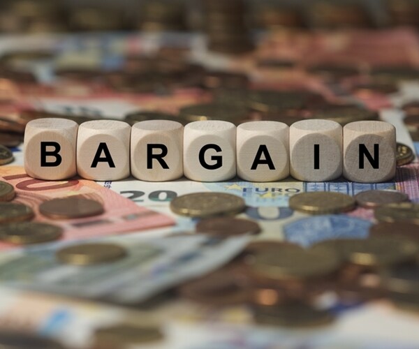 bargain spelled out in small wooden blogs amid global currency coins