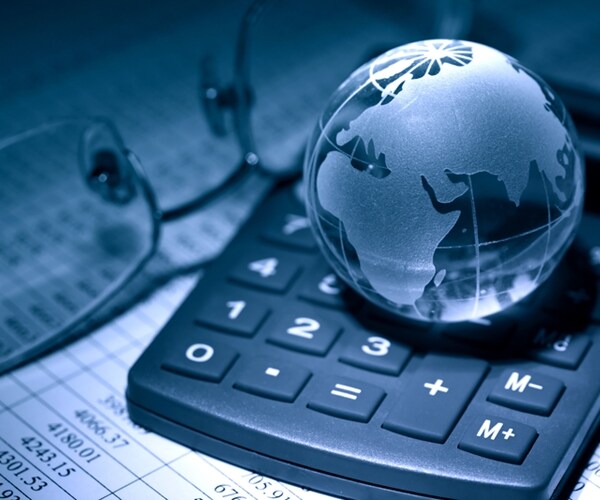 business concept. glass globe on calculator near spectacles on background with table of numbers

