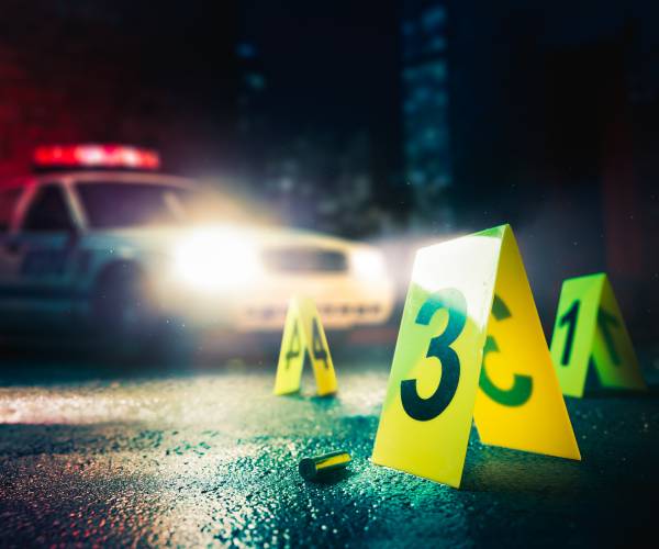 a bullet shell casing on the ground with a police car in the background