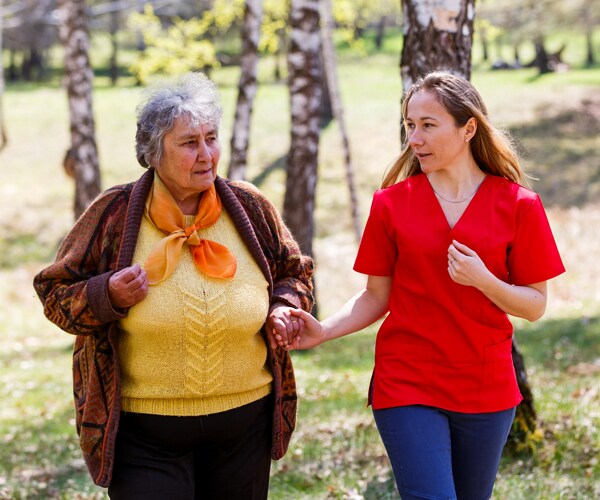 An elderly woman walking with her caretaker