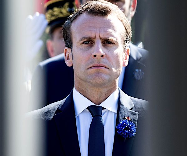 emmanuel macron stands stoically during an outdoor ceremony