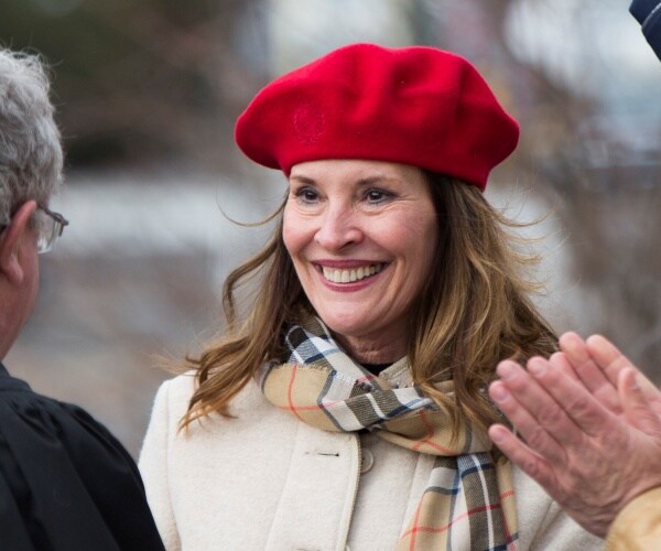 mcgeachin wearing a red hat and cream colored coat and plaid scarf