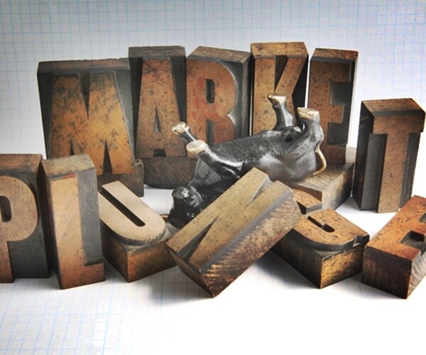 An upside-down bull figure in the middle of the words market plunge, some letters toppled 