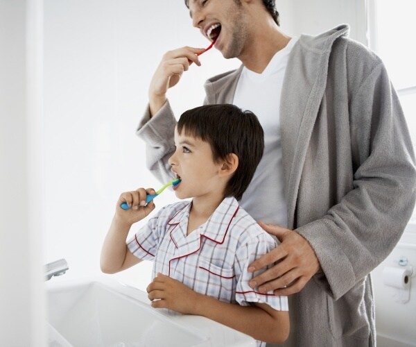 father and son brushing teeth