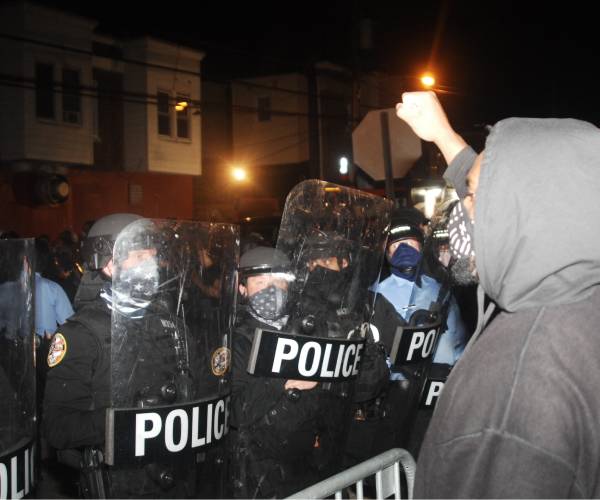 a protestor raises his fist facing a line of police officers