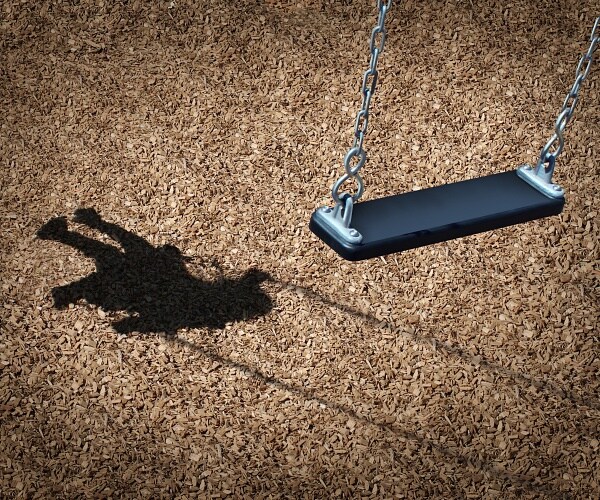 empty playground swing with child in shadow
