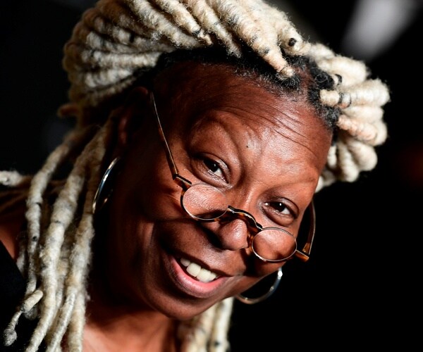 whoopi goldberg stands on gold carpet