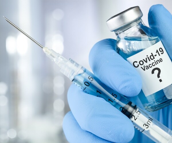 a gloved hand holds a syringe and a bottle with vaccine