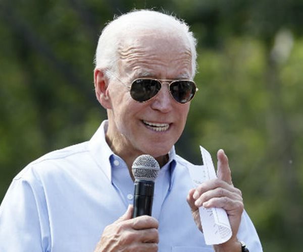 joe biden in aviator sunglasses faces to his left and gestures with his left hand 