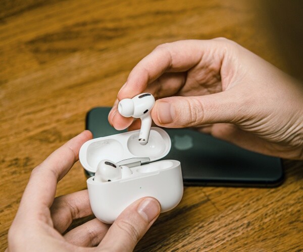 man's hands pulling AirPods out of packaging