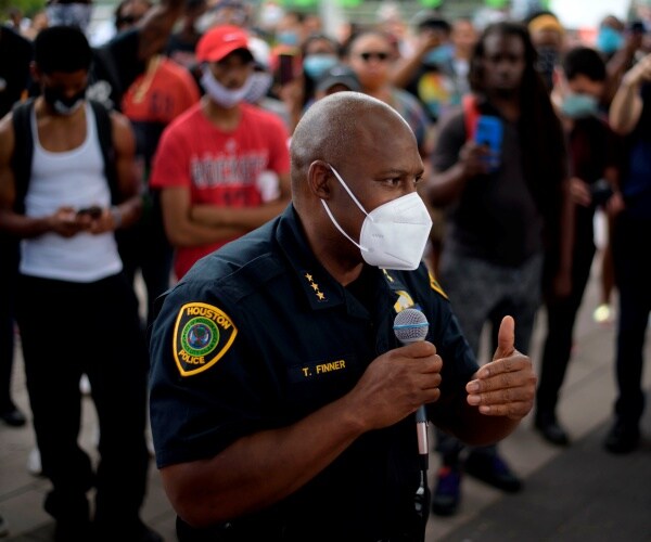 troy finner stands in a crowd wearing a mask