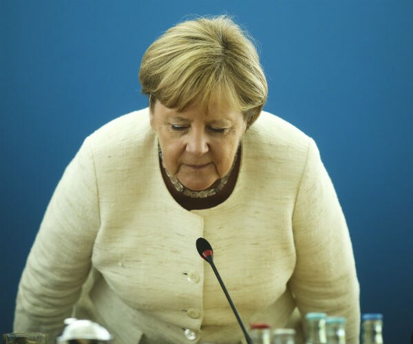 german chancellor angela merkel is shown in a creme suit